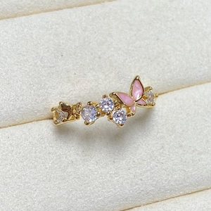 Macro shot of gold butterfly ring featuring pink enamel work and white zircon inlay