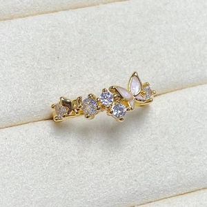 Macro detail of a golden butterfly ring featuring pink enamel wings and zircon accents