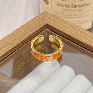 Detail view of a vintage gold-plated ring featuring orange enamel and pink floral patterns