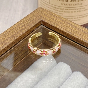 Macro shot of vintage gold-plated ring with red and pink enamel cross flower patterns