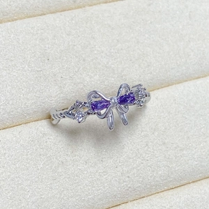 Close-up of silver butterfly ring with purple gems and twisted band details