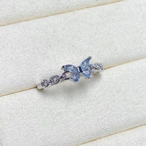 Macro shot of silver butterfly ring with light blue zircons and hollow chain band