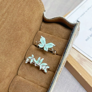 Détail de bagues papillon en argent avec émail vert menthe et zircons sur velours marron