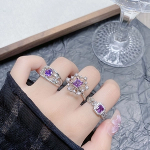 Detailed macro view of a three-piece purple zircon ring set on elegant model hands