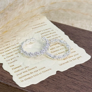 Detailed macro view of two minimalist silver open rings with floral and twisted patterns