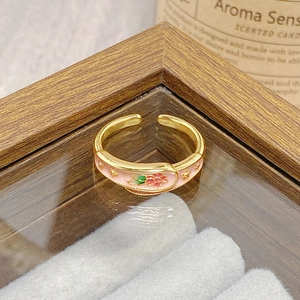 Close-up of vintage gold-plated open ring with pink enamel floral and star patterns