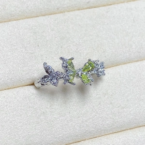 Detailed close-up of butterfly ring with light green crystals and micro-pave stones