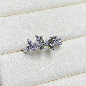 Detail of silver butterfly ring with olive green gems and sparkling zircon stones