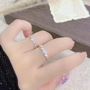 Macro shot of silver zircon rings with leafy details and square stone on dark background