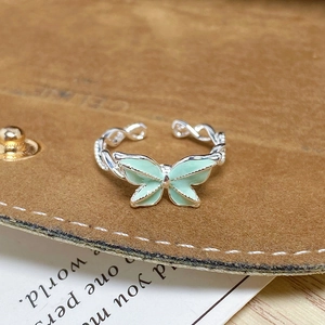 Détail d'une bague papillon en émail vert menthe avec un anneau tissé argenté