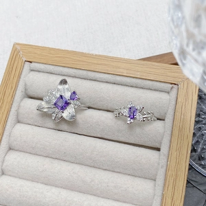 Close-up of purple zircon flower rings with silver band detail in a velvet jewelry box