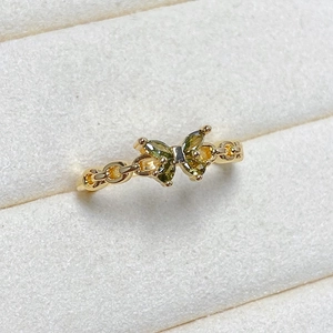 Detailed macro view of butterfly ring with olive green gems and gold chain band
