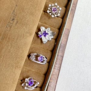 Close-up of four silver flower rings with purple zircons and diamonds in a jewelry box