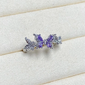 Macro detail of silver butterfly ring with four purple marquise-cut stones and zircon accents