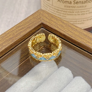 Macro view of vintage gold ring with blue enamel inlay and scalloped floral edge