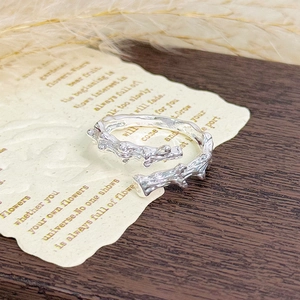 Macro shot of silver vine texture ring on vintage paper with natural branch design