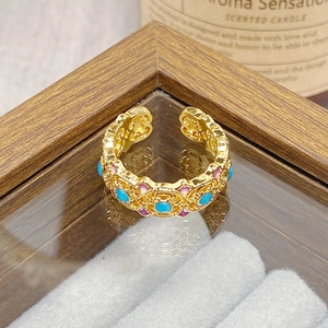 Close-up of vintage gold hollow ring with blue bead and colorful enamel details