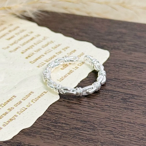 Detail of silver twisted rope ring featuring a textured braided finish and open band design