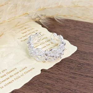 Macro shot of intricate hollow floral texture and cubic zirconia on silver ring