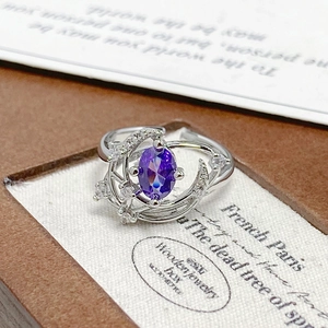 Macro shot of silver crescent moon and star ring with oval purple gemstone inlay