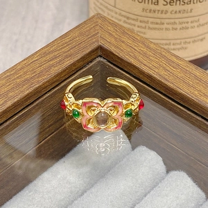 Close-up of vintage flower ring with pink enamel, brown gemstone, and gold band