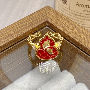 Macro shot of red enamel gourd ring with gold ginkgo leaf engraving and zircons