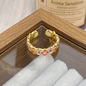 Macro detail of vintage gold open ring featuring pink and purple enamel flower patterns