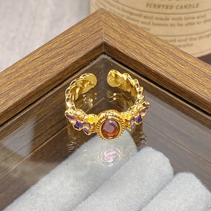 Macro detail of vintage gold open ring featuring purple gemstone and enamel butterfly petals