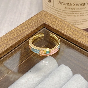 Detail view of vintage adjustable ring with pink floral enamel and golden finish on stand