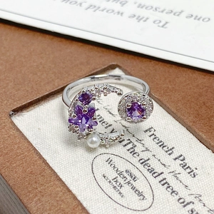 Macro detail of crescent moon ring with purple zircon star and a white pearl accent