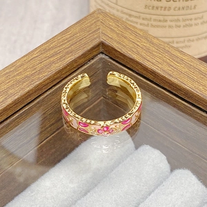 Detail of vintage enamel flower open ring with gold plated floral patterns on a display