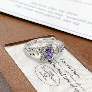 Macro detail of purple zircon flower ring with silver leaf engravings on the band
