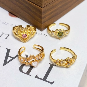 Detailaufnahme von vier Vintage Goldringen mit Herz, Krone und Perlenmotiven