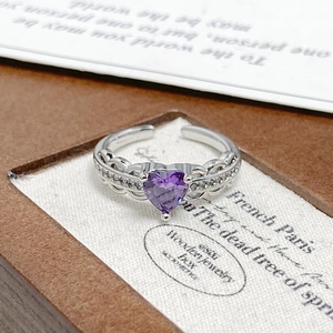 Macro detail of heart-shaped purple zircon ring with silver hollow wave band and small diamonds