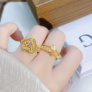 Makroaufnahme goldener Vintage-Ringe mit violettem Herz-Edelstein und floralen Perlenakzenten