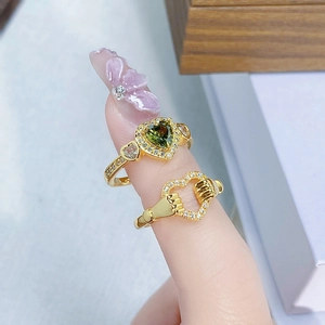 Nahaufnahme von Vintage Goldringen mit grünem Herz-Zirkon und kreativem Handgesten-Design