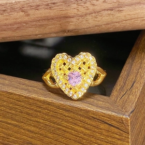 Detail eines Vintage Herzrings in Gold mit rosa Zirkon und geflochtener Metalltextur