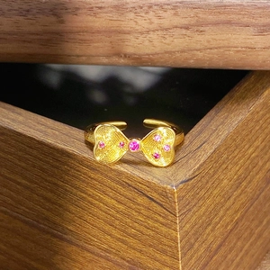Detailaufnahme eines Vintage-Bogenrings in Gold mit rosa Zirkon auf Holzbox
