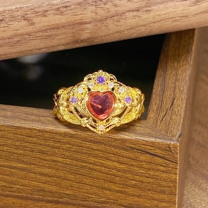 Makro-Detail des kronenförmigen Goldrings mit herzrotem Stein und Vintage-Gravur
