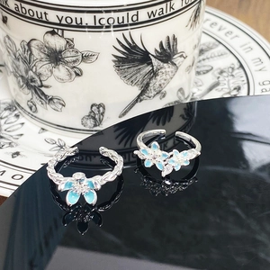 Macro view of blue enamel flower rings with crystals on silver adjustable bands