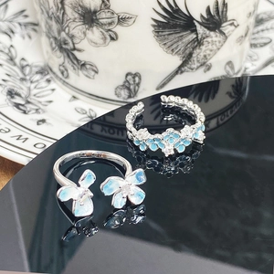 Macro detail of silver floral enamel rings with light blue flowers and micro zircon inlays