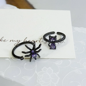 Close-up of gothic spider and cat rings featuring purple heart-shaped zircons