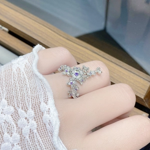 Detailed view of silver flower ring with purple gemstone on a lace sleeve hand