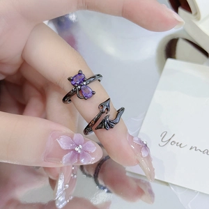 Close-up of gothic black rings with purple zircons featuring cat and bat wing designs