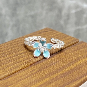 Close-up of sky blue enamel flower ring with twisted silver rope band and zircon center