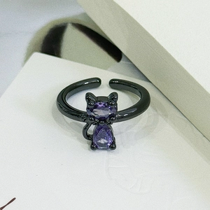 Detail of a dark black cat-shaped open ring featuring purple drop-shaped gemstones