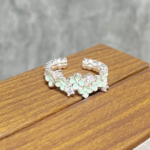 Macro detail of silver open ring featuring green enamel flowers and sparkling zircons