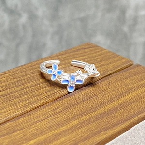 Close-up of floral enamel ring with blue gradient petals and small zircon centers