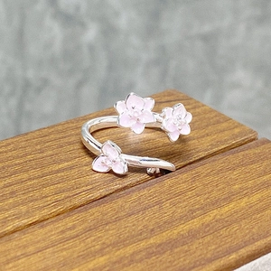 Detailed macro view of pink enamel cherry blossom flowers on a silver adjustable ring