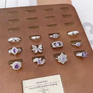 Collection of 11 purple zircon rings with silver adjustable bands and floral star designs